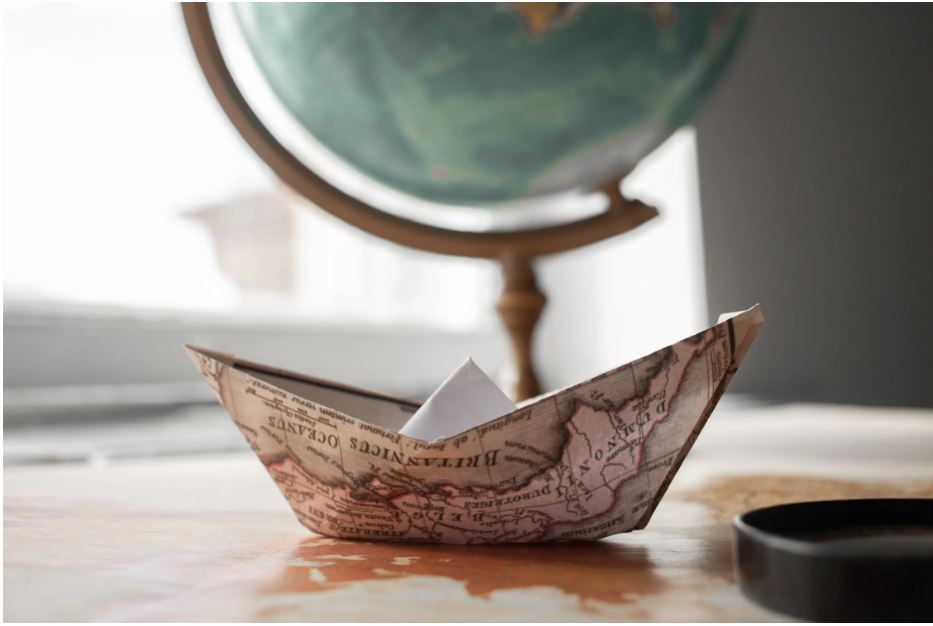 A paper boat in front of a globe